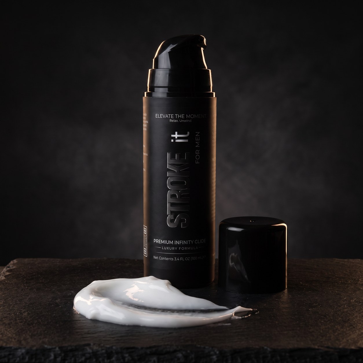 Stroke it bottle beside a swirl of pure white cream on dark slate